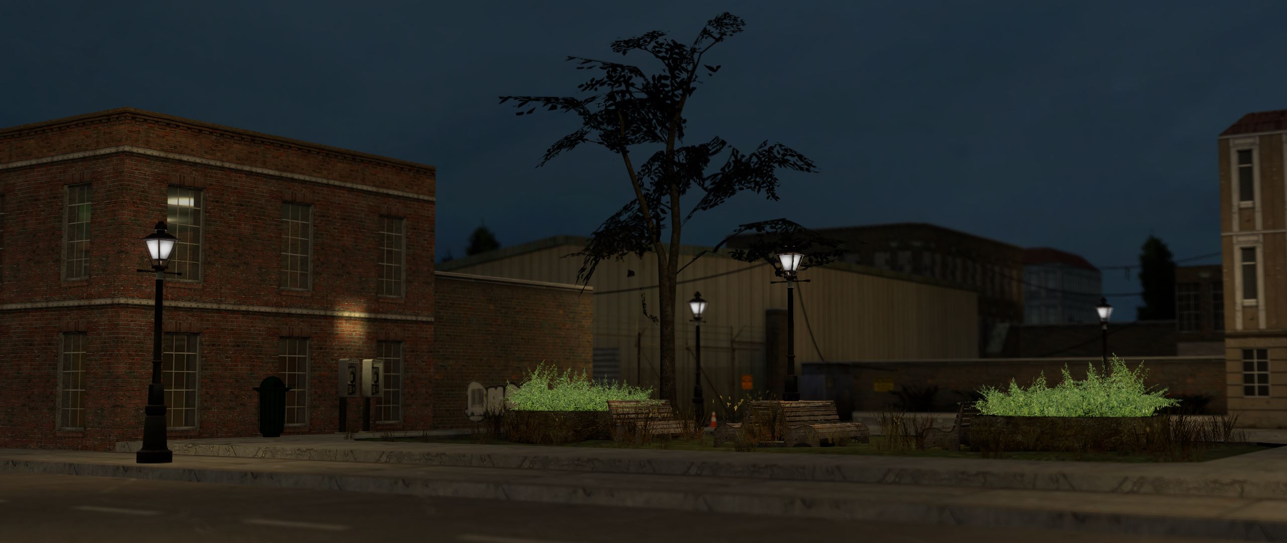 A peaceful park at night with benches and bushes by the road. Payphones and a trash can line the left of the park, and a fence can be seen in the background. The area is illuminated by streetlamps.